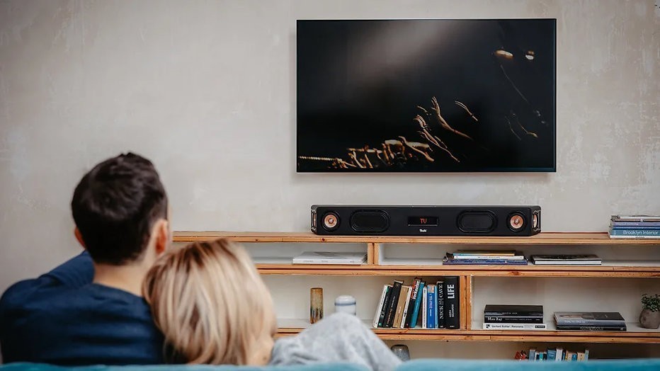 Verliefd koppeltje luistert naar prachtig geluid uit een speaker van Teufel en kijkt ook tv Verliefd koppeltje luistert naar prachtig geluid uit een speaker van Teufel en kijkt ook tv