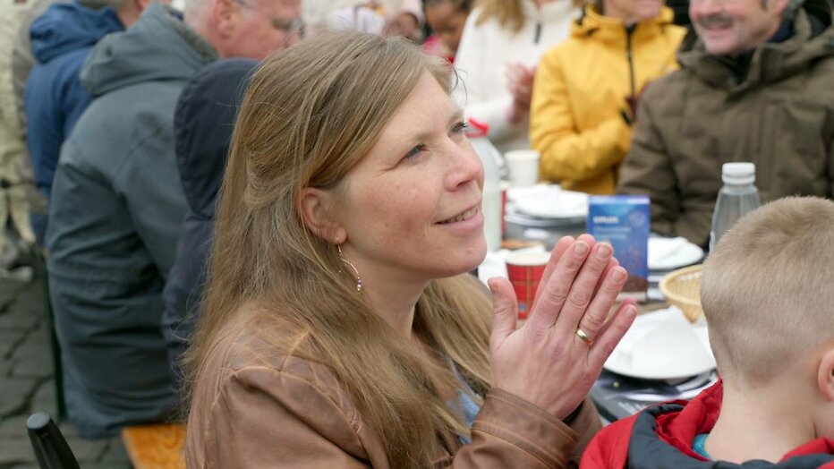 Moeder Gerdien Blom ziet haar man prediken voor grote groep mensen.